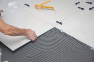 Professional installation of bathroom floor tiles with leveling and adhesive